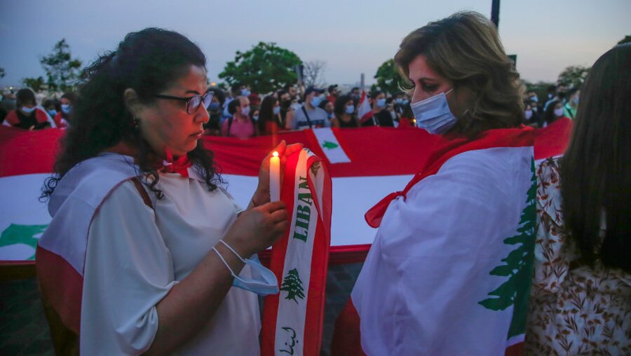 Eine Frau hält eine Kerze während einer Mahnwache zum Gedenken an die Opfer / © Michel Euler (dpa)