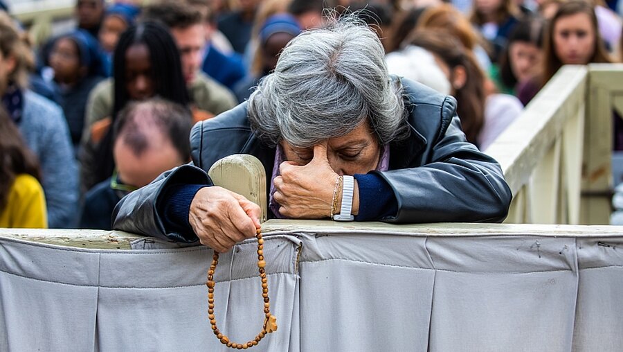 Eine Frau betet den Rosenkranz / © Stefano Dal Pozzolo (KNA)