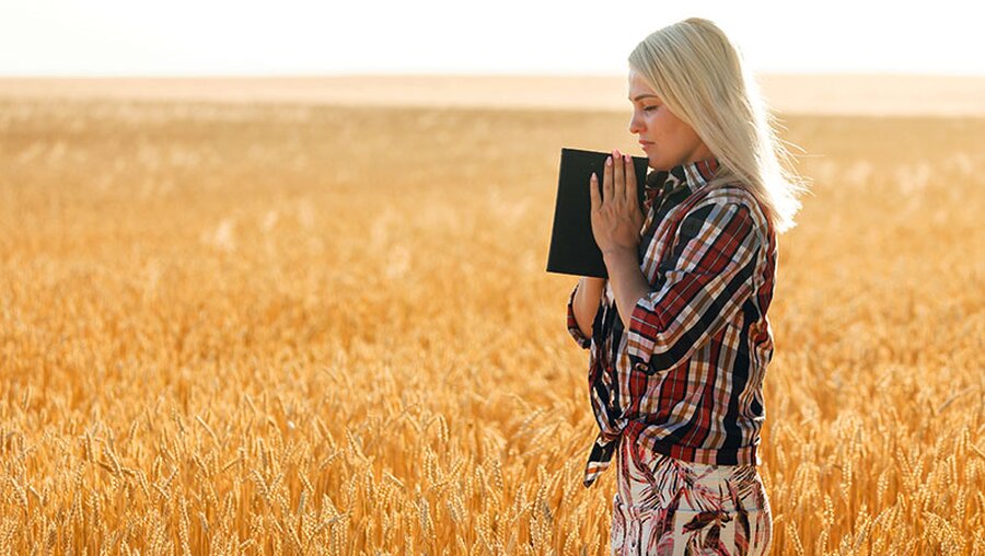 Eine Frau mit einer Bibel in der Hand auf einem Feld / © Andrew Angelov (DR)