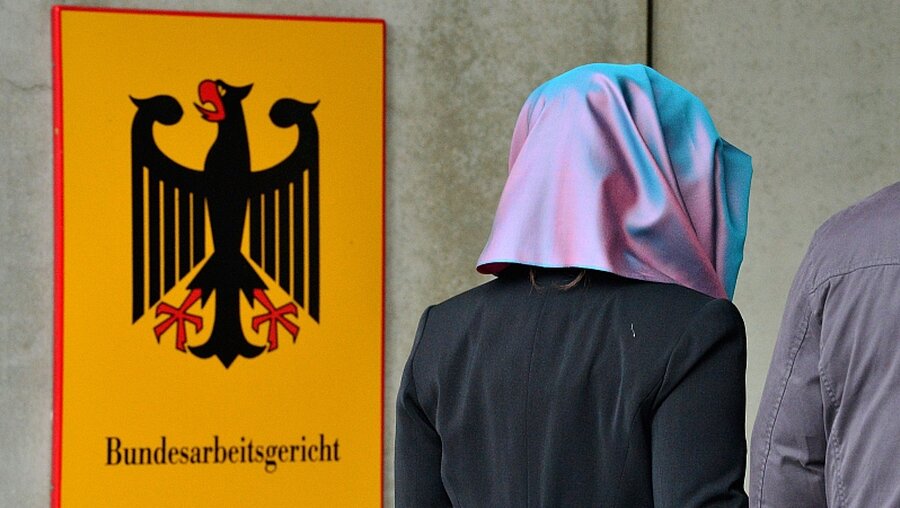 Symbolbild: Eine Frau mit Kopftuch vor dem Bundesarbeitsgericht / © Martin Schutt (dpa)