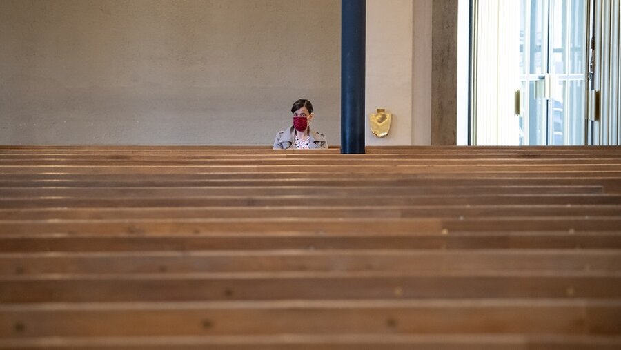 Eine Frau mit Mundschutz verfolgt einen Gottesdienst in München / © Sven Hoppe (dpa)