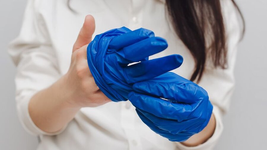 Eine Frau zieht ihre medizinischen Handschuhe aus / © Shchus (shutterstock)