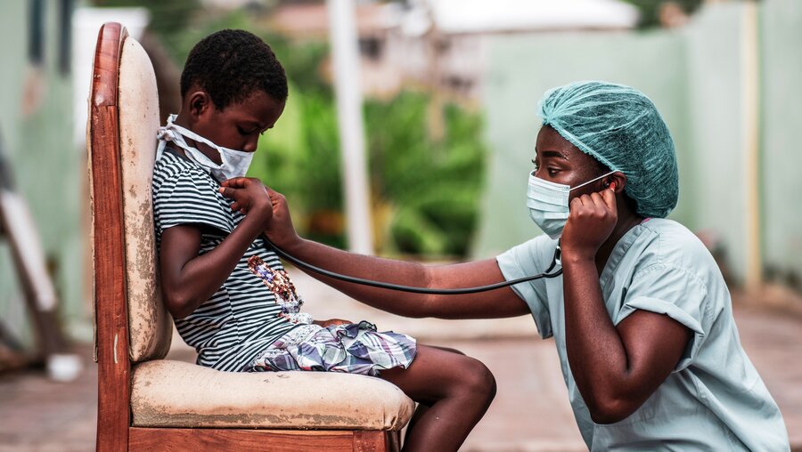 Eine Krankenschwester mit Mundschutz untersucht einen Jungen / © Yaw Niel (shutterstock)