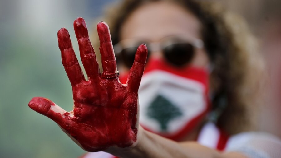 Eine libanesische Aktivistin mit rot bemalter Hand / © Hussein Malla (dpa)