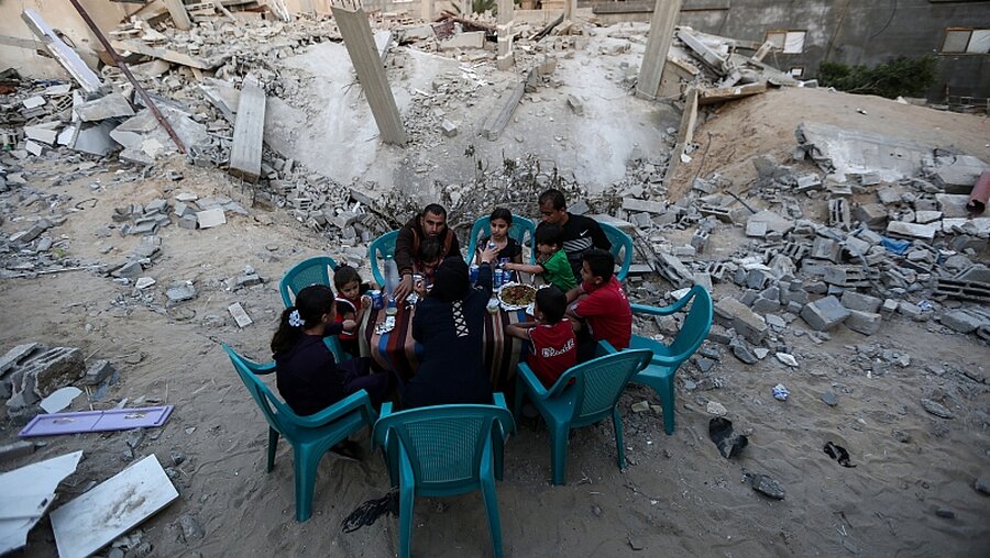 Eine palästinensische Familie frühstückt neben ihrem zerstörten Haus in der Stadt Rafah / ©  XinHua (dpa)