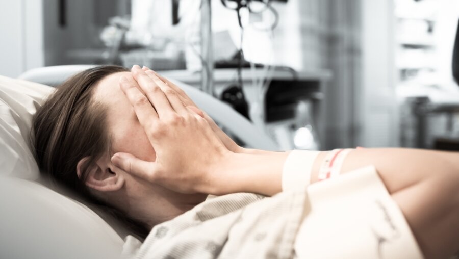 Eine verzweifelte Person in einem Krankenhausbett / © KieferPix (shutterstock)