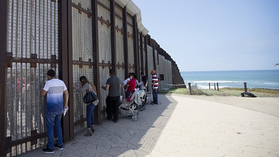 Menschen am Grenzzaun, der die USA und Mexiko trennt. / © Gregory Bull (dpa)