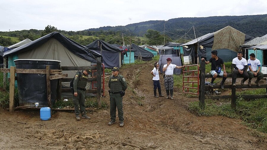 Zwei Polizisten stehen in Buenavista (Kolumbien) am Eingang der Mariana Paez Demobilisierungszone, eine der vielen ländlichen Camps der Farc-Rebellen.  / © Fernando Vergara (dpa)