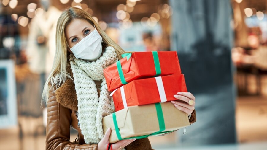 Frau mit Mundschutz und Weihnachtsgeschenken beim Einkaufen / © Kamil Macniak (shutterstock)
