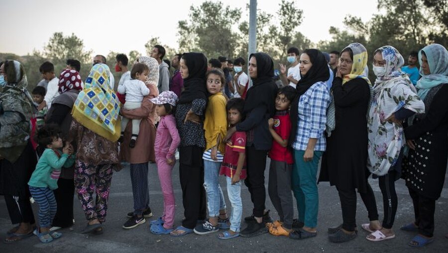 Frauen stehen an, um Essen zu erhalten, in der Nähe des ausgebrannten Flüchtlingslagers Moria / © Socrates Baltagiannis (dpa)