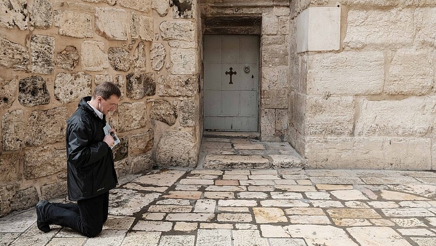Gläubiger betet vor den geschlossenen Türen der Grabeskirche / © Nir Alon (dpa)