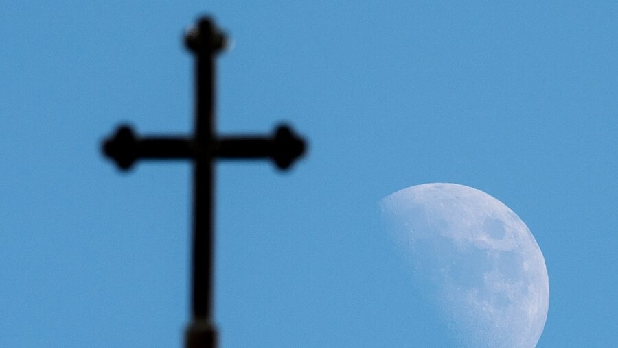 Mond über einem Kirchenkreuz / © Patrick Pleul (dpa)
