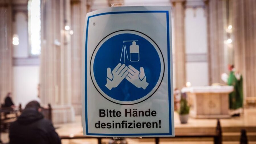 Hinweisschild mit der Aufschrift "Bitte Hände desinfizieren" in einer Kirche / © Lars Berg (KNA)
