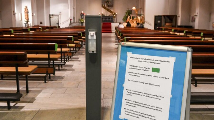 Hinweistafel und Desinfektionsmittel in einer Kirche / © Harald Oppitz (KNA)