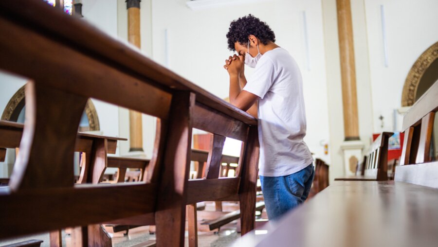 Ein junger Mann betet in einer Kirche / © Jair Ferreira Belafacce (shutterstock)