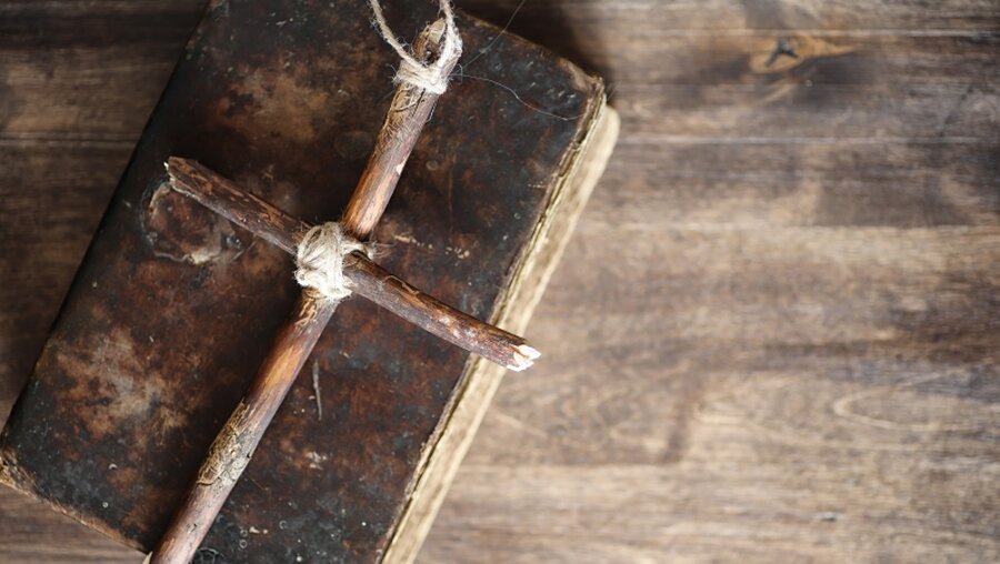 Holzkreuz auf einem alten Buch / © alexkich (shutterstock)