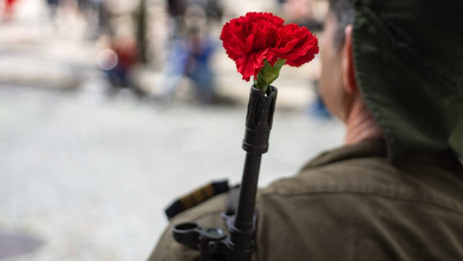 Im Gewehrlauf eines Soldaten steckt eine Nelke / © Max Zvonarev (shutterstock)