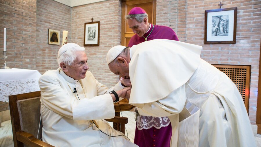 Papst Franziskus küsst die Hand des emeritierten Papstes Benedikt XVI. (l.) (Archiv) / © Vatican Media/Romano Siciliani (KNA)