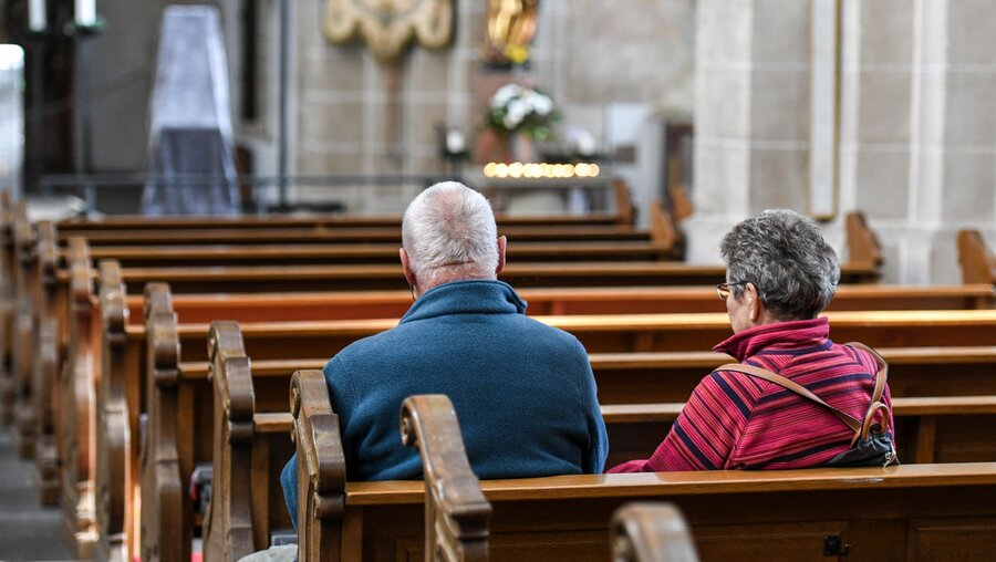 Ein Mann und eine Frau sitzen auf einer Kirchenbank / © Harald Oppitz (KNA)