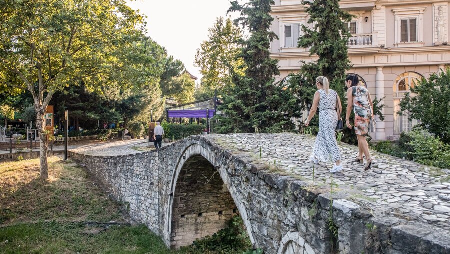 Zwei Frauen gehen über eine alte Brücke in Tirana (Albanien) / © Alessio Mamo (KNA)