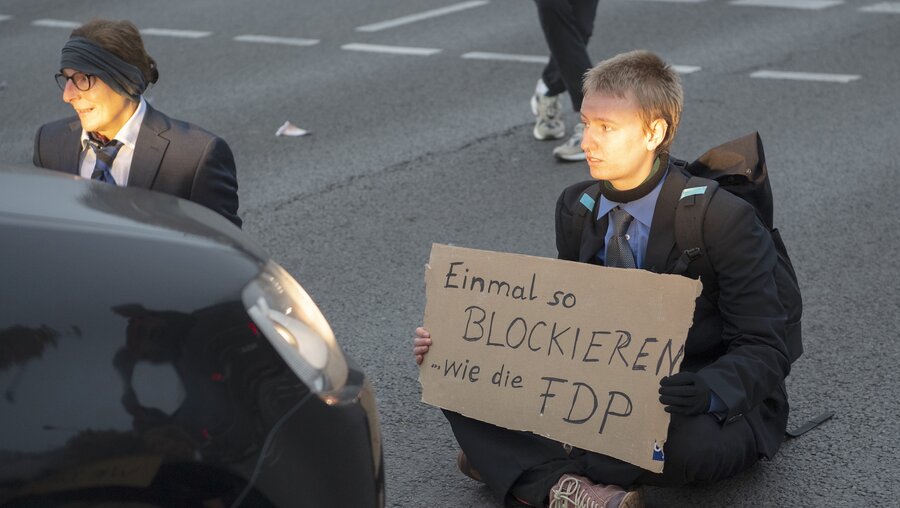 Aktivisten der letzten Generation sitzen auf einer Kreuzung an der Landsberger Allee in Berlin. / © Paul Zinken (dpa)