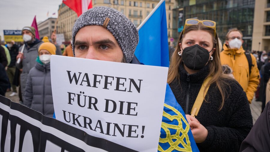 Ein Demonstrant am 24. Februar 2022 in Berlin mit einem Plakat mit der Aufschrift Waffen für die Ukraine! / © Jannis Chavakis (KNA)