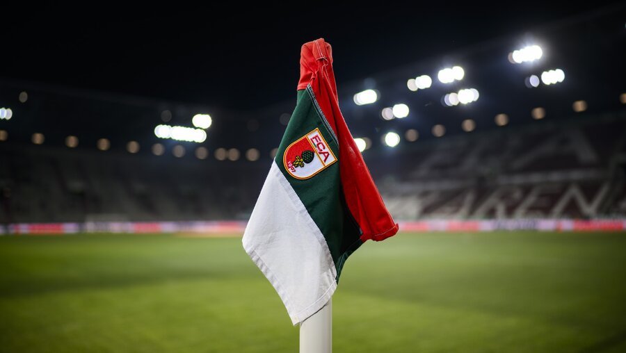 Die Eckfahne des FC Augsburg steht mit Logo im Stadion. / © Tom Weller (dpa)
