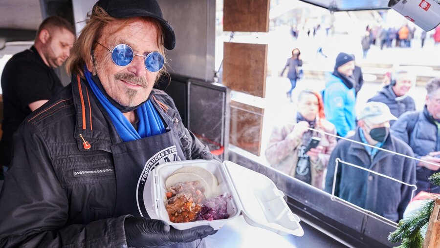 Frank Zander steht im Caritas-Foodtruck und verteilt warme Mahlzeiten an Obdachlose und bedürftige Menschen auf dem Alexanderplatz (Archiv) / © Annette Riedl (dpa)
