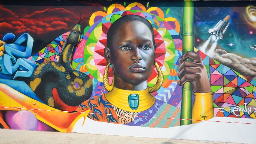 Die Malerei zeigt eine junge Afrikanerin in traditioneller Kleidung. Das Graffito wurde an der Hafenmauer von Cotonou gesprüht, anlässlich des Graffiti-Festivals Effet Graff in Benin. / © Katrin Gänsler (KNA)