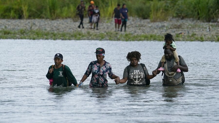 Haitianische Migranten waten durch den Tuquesa-Fluss in Bajo Chiquito in Panama, nachdem sie durch die Darien-Kluft gewandert sind / © Arnulfo Franco/AP/dpa +++ dpa-Bildfunk +++ (dpa)