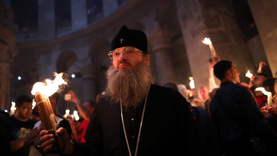 Ein orthodoxer Christ mit brennenden Kerzen in der Hand bei der Zeremonie des "Heiligen Feuers" in der Grabeskirche in Jerusalem während der Osterfeierlichkeiten an Karsamstag am 15. April 2017. / © Corinna Kern (KNA)