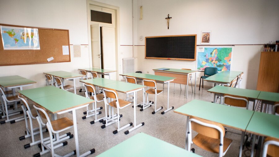 Leere Schulklasse mit Stühlen und Schulbänken. An der Wand über der Tafel hängt ein Kreuz. / © Cristian Gennari/Romano Siciliani (KNA)