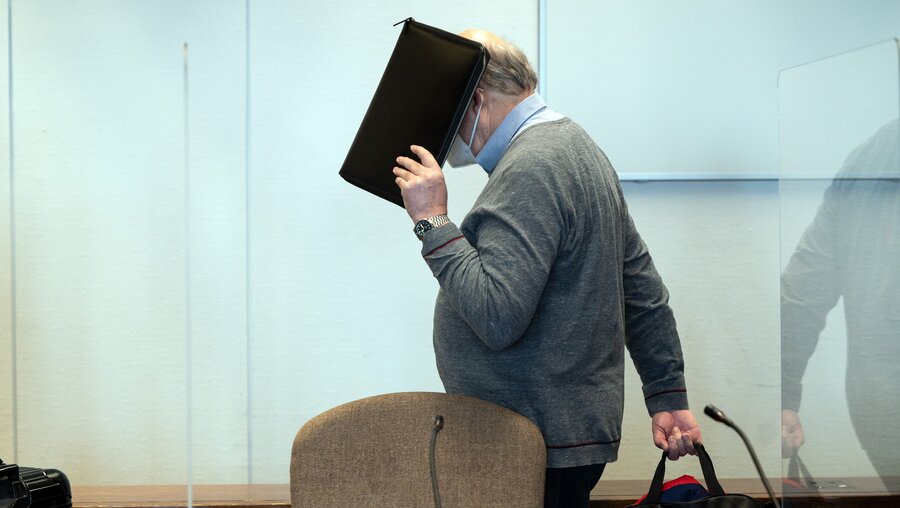 Köln: Der angeklagte katholische Priester U. hält sich im Gerichtssaal eine Mappe vor das Gesicht / © Federico Gambarini (dpa)