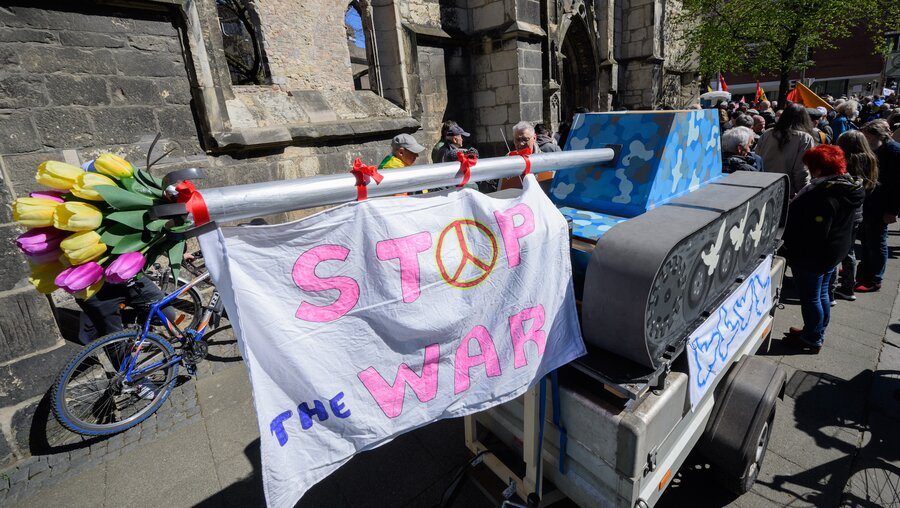 Ein nachgebauter Panzer mit Blumen und einem Plakat mit der Aufschrift 'Stop the war' beim Ostermarsch 2022 in Hannover. / © Julian Stratenschulte (dpa)
