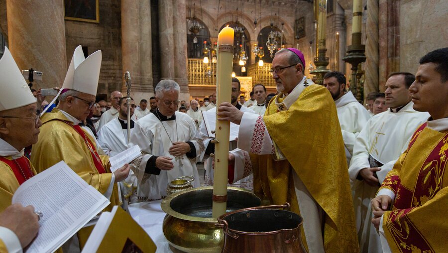 Erzbischof Pierbattista Pizzaballa, Lateinischer Patriarch von Jerusalem, taucht die Osterkerze in Weihwasser  / © Andrea Krogmann (KNA)