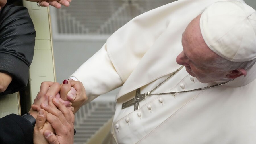 Papst Franziskus hält Hände von mehreren Gläubigen / © Gregorio Borgia/AP (dpa)