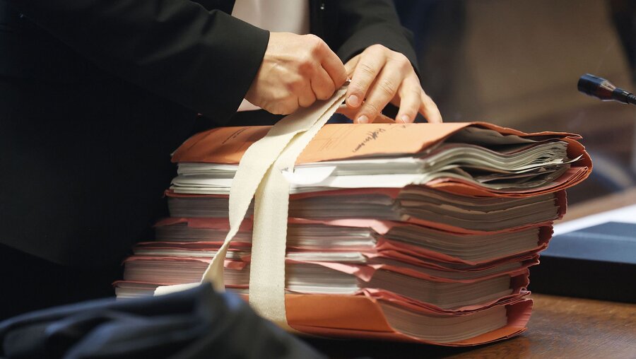 Symbolbild: Eine Anwältin schnürt im Gerichtssaal Prozessunterlagen auf / © Oliver Berg (dpa)
