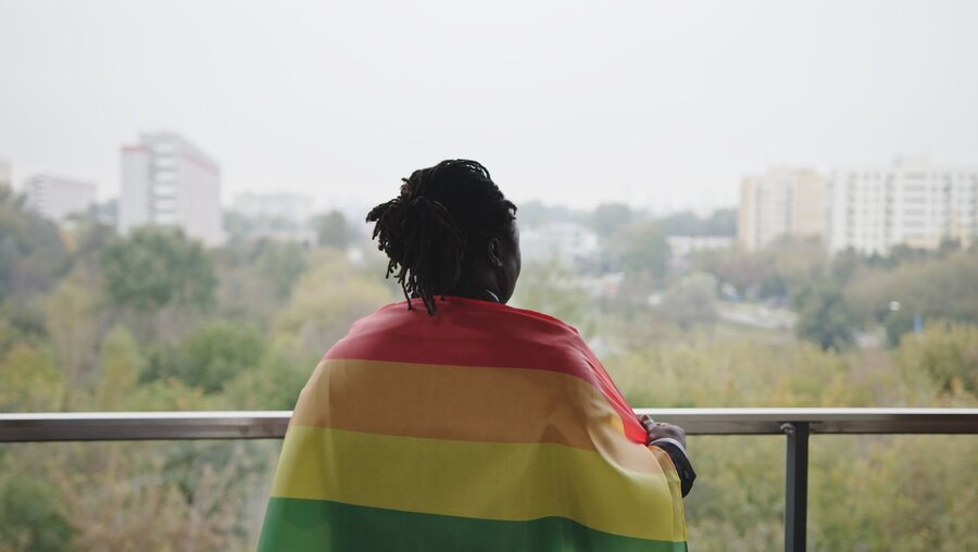 Eine schwarze Person mit Regenbogenflagge / © CameraCraft (shutterstock)