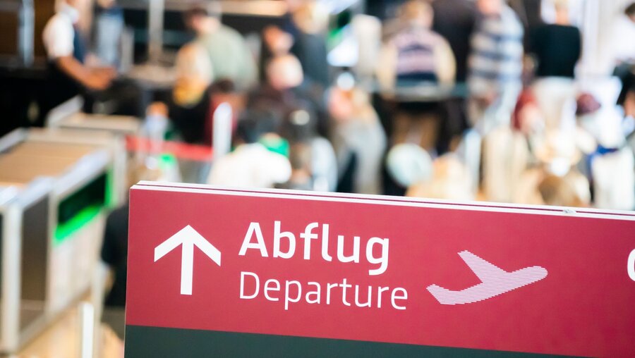 Menschen stehen am Flughafen an der Sicherheitskontrolle Schlange / © Christoph Soeder (dpa)