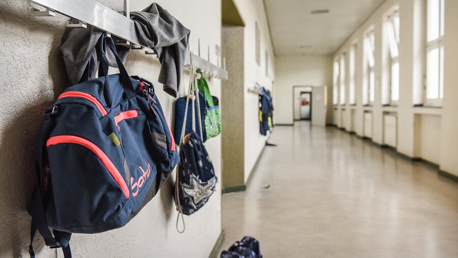 Jacken und Taschen hängen in einem Schulflur  / © Julia Steinbrecht (KNA)