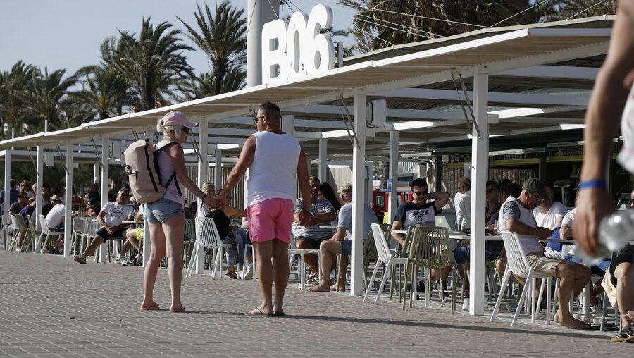 Spanien, Palma: Menschen gehen am Ballermann 6 am Strand von Arenal vorbei / © Clara Margais (dpa)