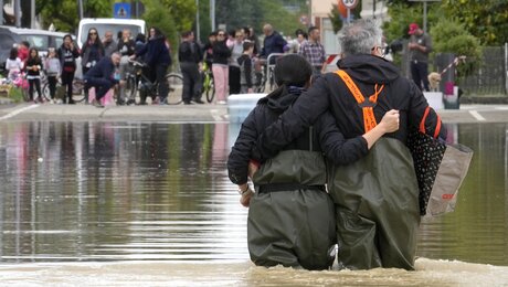 Ein Paar geht auf einer überfluteten Straße. Nach den Unwettern und Überschwemmungen in Italien ist die Anzahl der Opfer weiter gestiegen. / © Luca Bruno/AP (dpa)