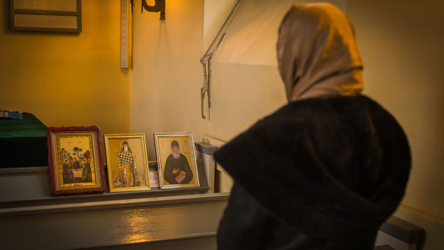 Eine Frau steht vor drei Ikonen / © Jannis Chavakis (KNA)