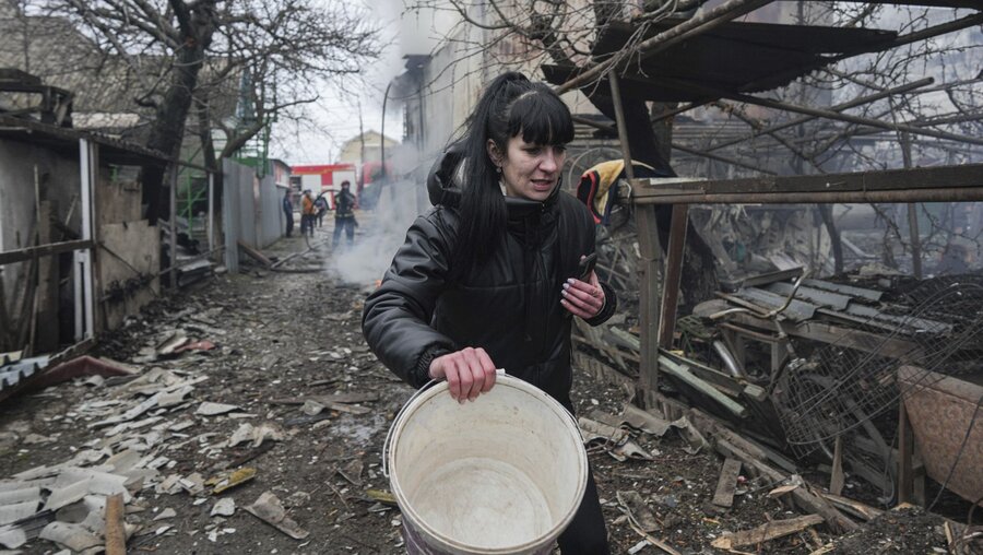Ukraine, Mariupol: Eine Frau geht an den Trümmern nach russischem Beschuss vorbei / © Evgeniy Maloletka (dpa)