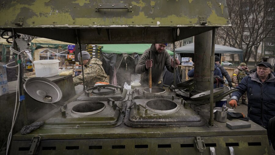 Menschen kochen im Freien für ukrainische Soldaten und Mitglieder des Zivilschutzes in Kiew / © Vadim Ghirda (dpa)