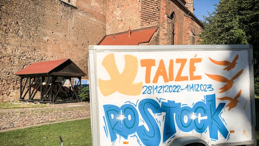 Ein Anhänger vor der Kirche Sankt Petri in Rostock wirbt am 31. August 2022 für das bevorstehende europäische Taize-Jugendtreffen in Rostock. / © Nicola Trenz (KNA)