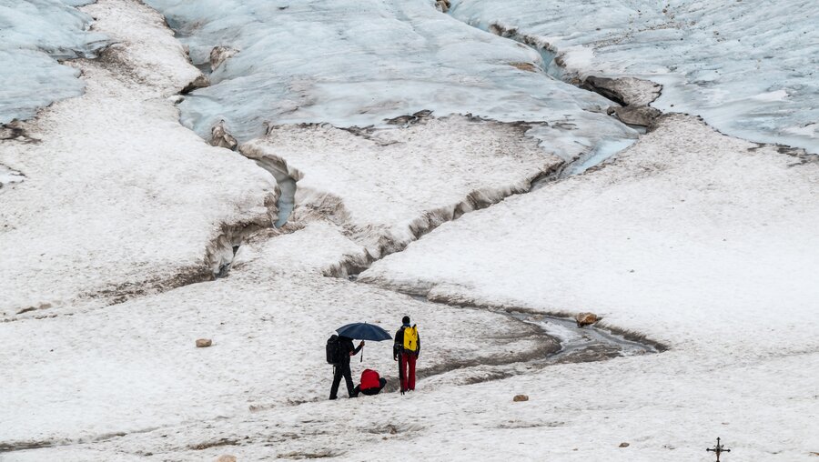 Touristen gehen auf den Resten des Gletschers auf der Zugspitze spazieren. / © Peter Kneffel (dpa)