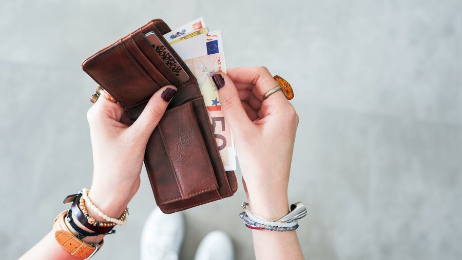 Eine Frau mit einem Geldbeutel und Geldscheinen / © sebra (shutterstock)