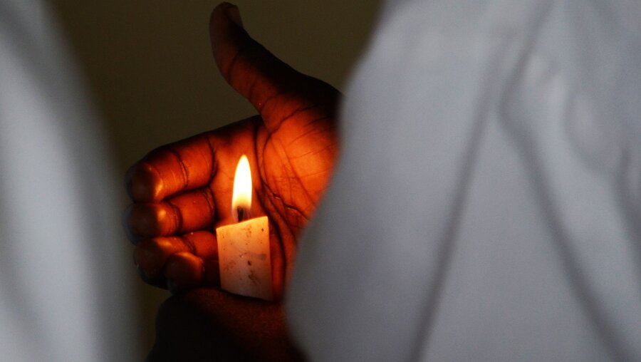 Mann mit einer Kerze in einer südafrikanischen Kirche / © Adriana Mahdalova (shutterstock)