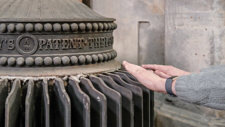 Hände wärmen an einem sehr alten, funktionierenden Dampfkessel in einer Kathedrale in Ely, Cambridgeshire, UK. / © Nick Beer (shutterstock)